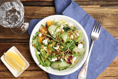 Photo of Delicious salad with lentils, vegetables and feta cheese served on wooden table, flat lay