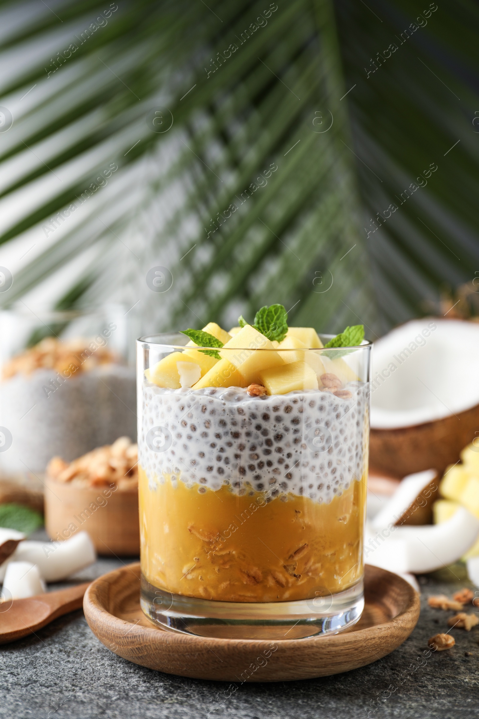 Photo of Delicious chia pudding with mango, mint and granola on grey table