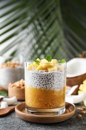 Delicious chia pudding with mango, mint and granola on grey table