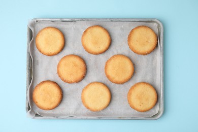 Photo of Tray with tasty sweet sugar cookies on light blue background, top view