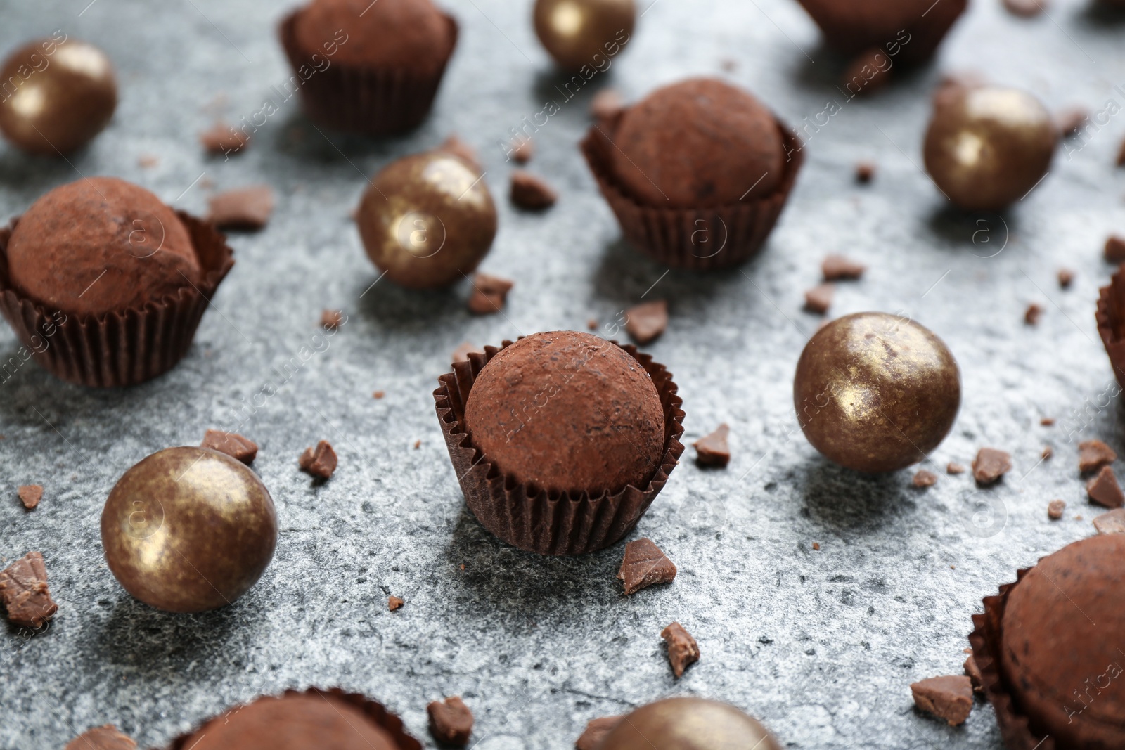 Photo of Different delicious chocolate candies on grey table, closeup