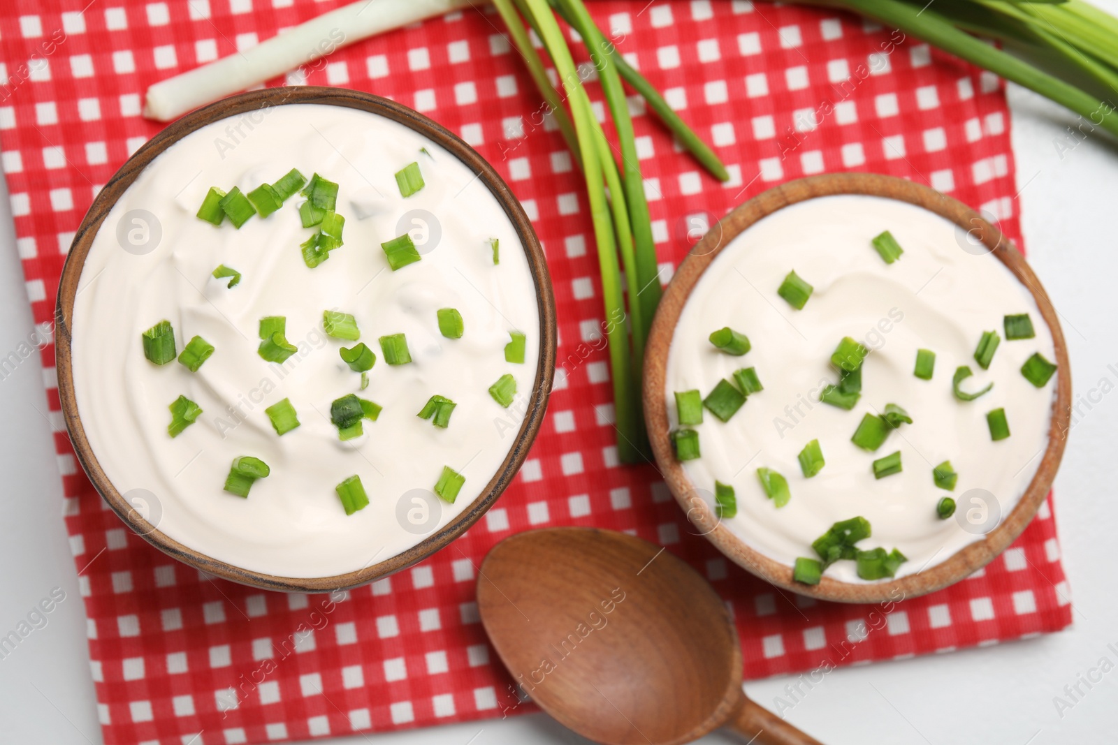 Photo of Fresh sour cream with onion on fabric, flat lay