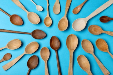 Set of new wooden spoons on blue background, flat lay