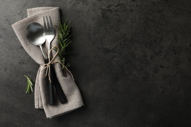 Photo of Stylish setting with cutlery and napkin on black table, top view. Space for text