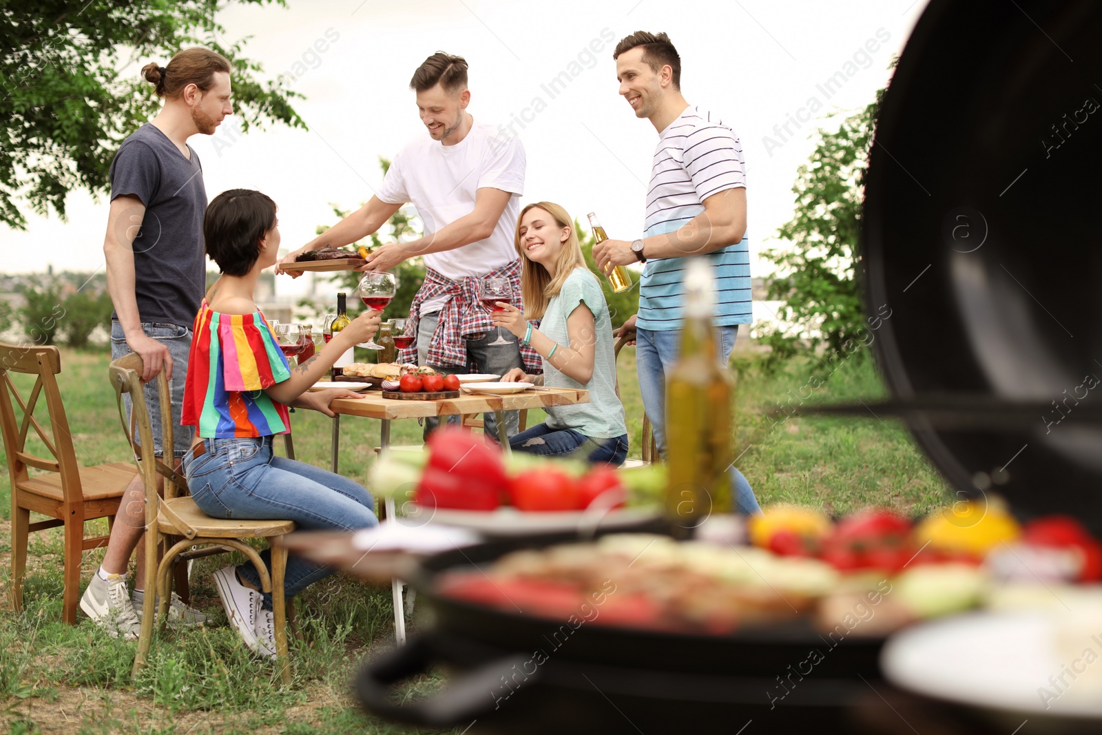 Photo of Young people having barbecue at table outdoors