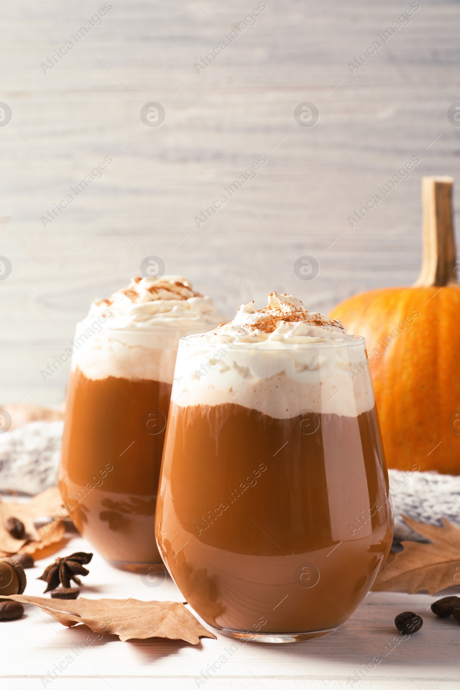Photo of Glasses with tasty pumpkin spice latte on wooden table