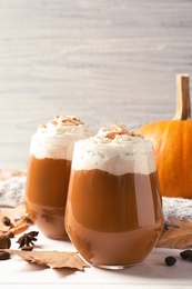 Glasses with tasty pumpkin spice latte on wooden table