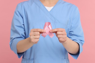 Photo of Mammologist with pink ribbon on color background, closeup. Breast cancer awareness