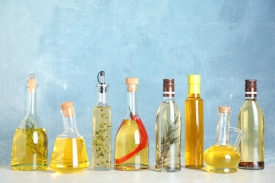 Photo of Different sorts of cooking oil in bottles on light grey table