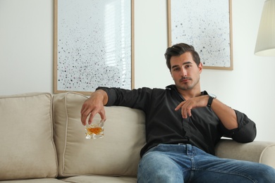 Photo of Young man with glass of whiskey at home