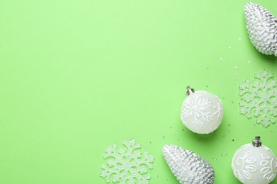 Flat lay composition with Christmas balls and decor on green background, space for text