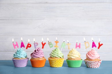 Birthday cupcakes with burning candles on blue wooden table