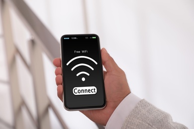 Image of Man connecting to WiFi using mobile phone indoors, closeup