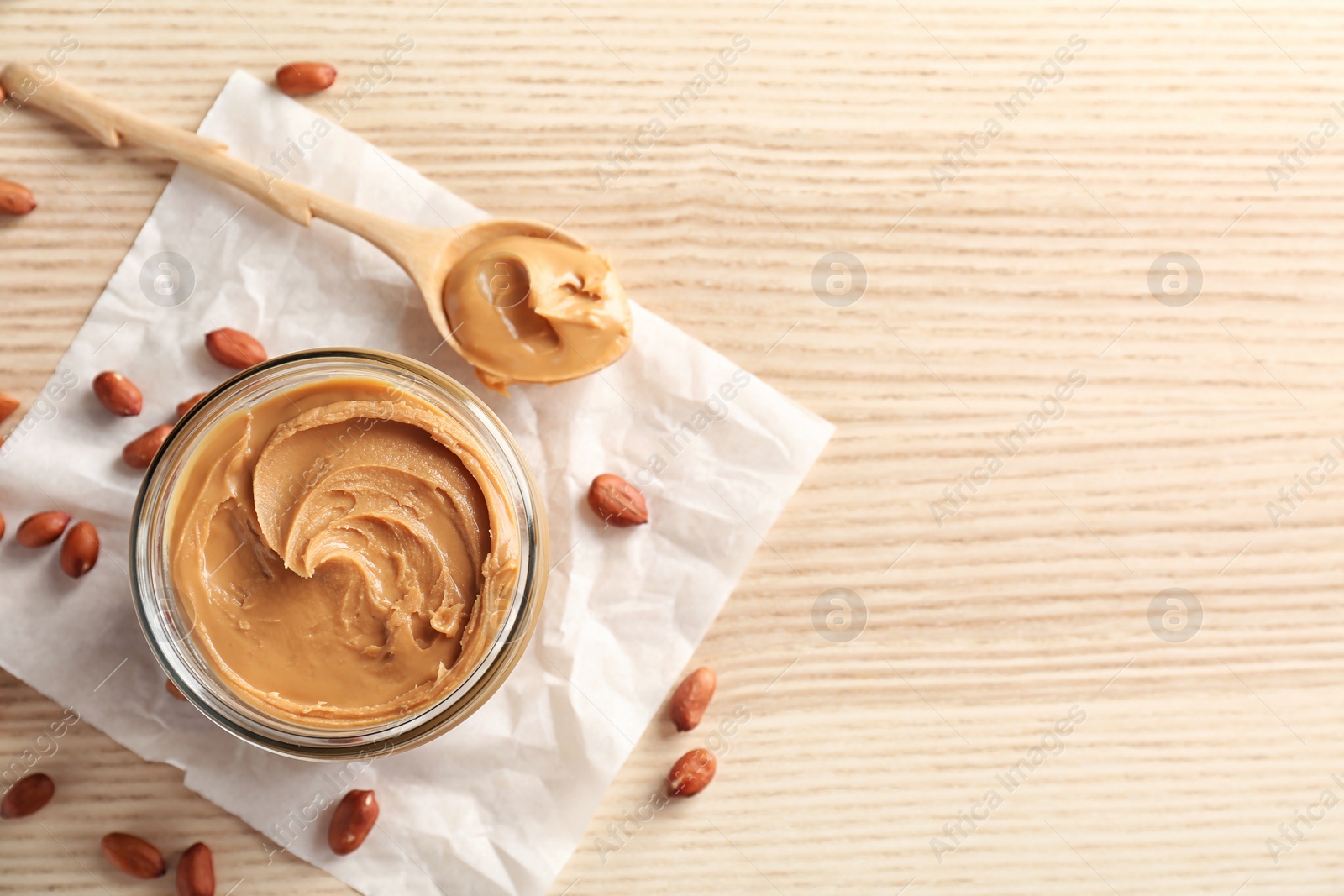 Photo of Jar and spoon with creamy peanut butter on table