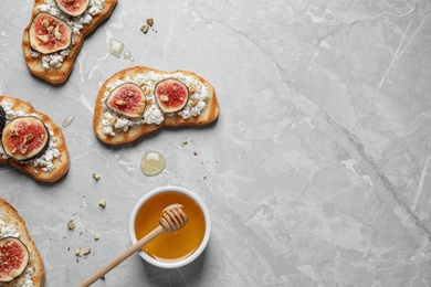 Photo of Bruschettas with cheese, figs and honey on marble table, flat lay. Space for text