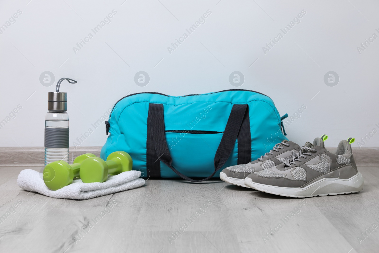 Photo of Stylish sports bag and different gym stuff on wooden floor indoors