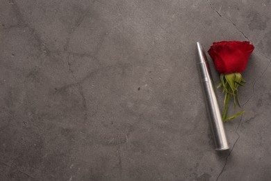 Photo of Bullet and beautiful rose on grey textured table, flat lay. Space for text