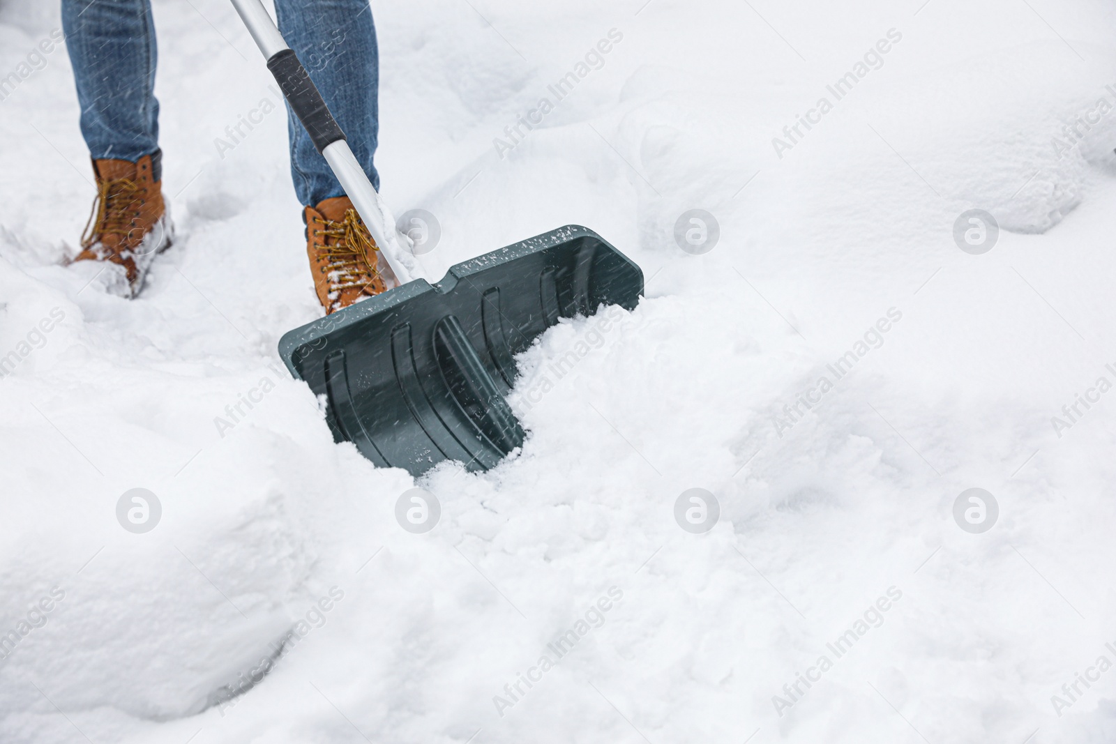 Photo of Man cleaning snow with shovel outdoors, closeup