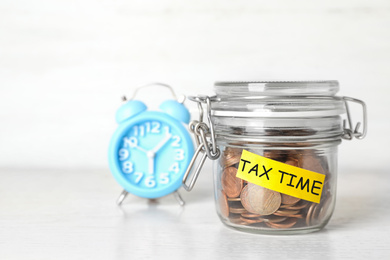 Image of Time to pay taxes. Coins in glass jar with label on table 