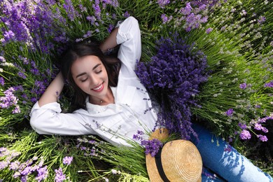 Young woman lying in lavender field on summer day, top view