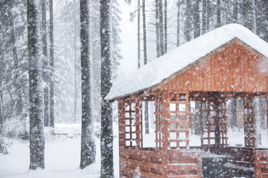 Photo of Modern wooden gazebo on snowy day. Winter vacation