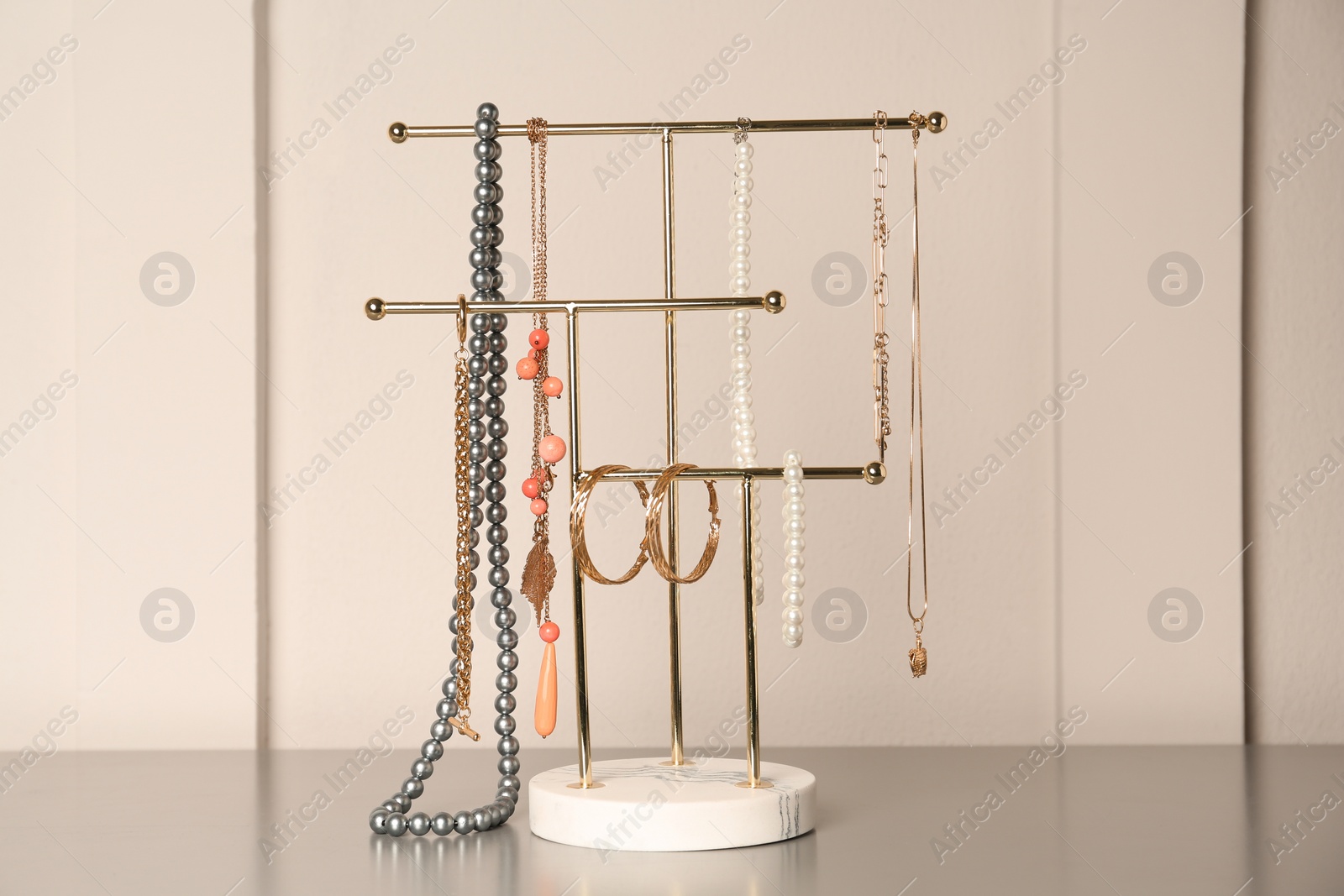 Photo of Holder with set of luxurious jewelry on grey table