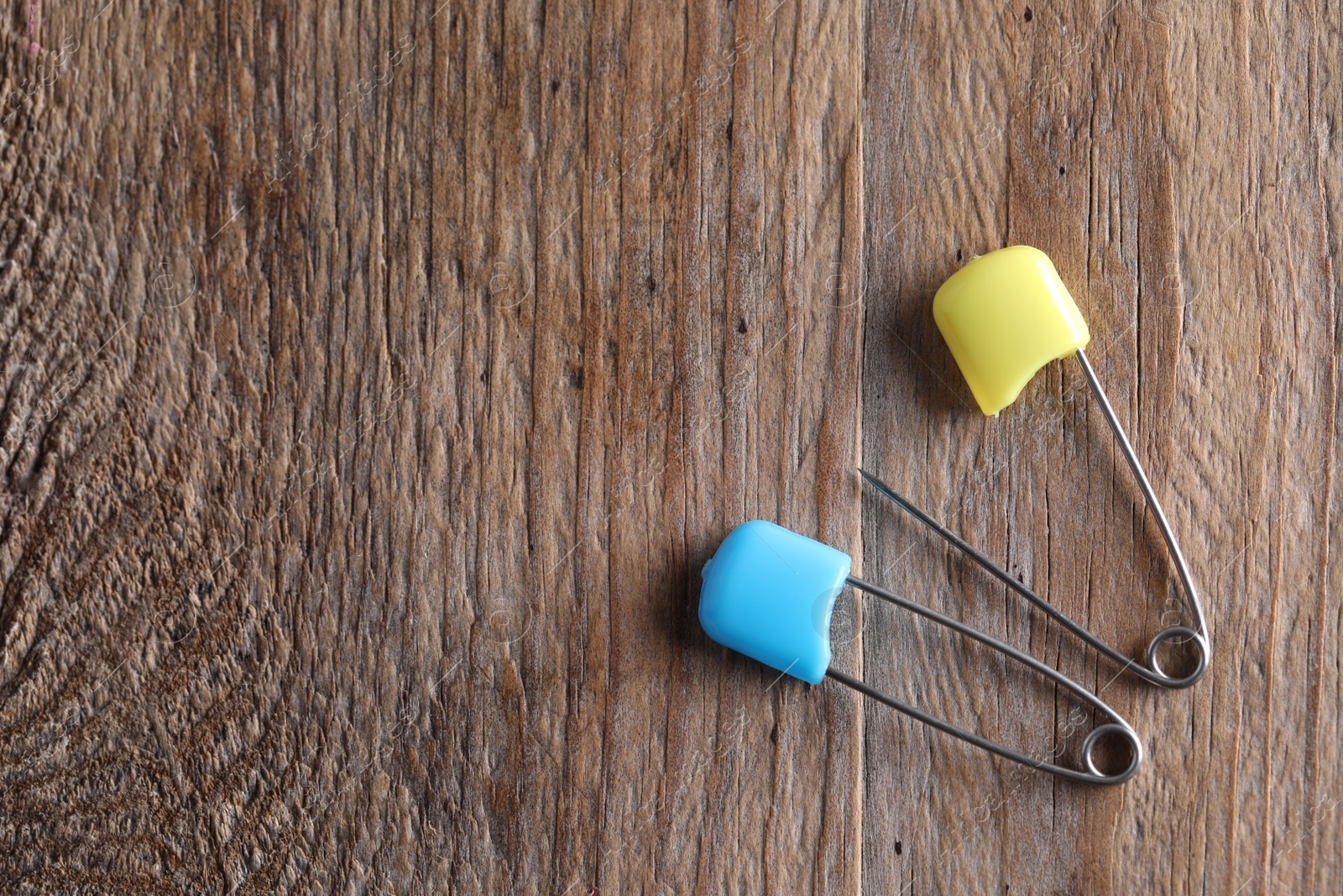 Photo of New safety pins on wooden table, flat lay. Space for text