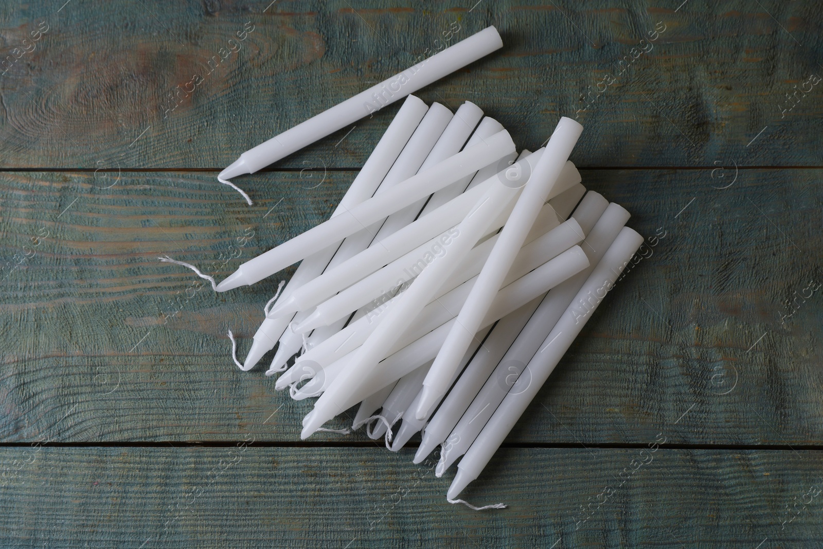 Photo of Many church wax candles on old wooden table, flat lay