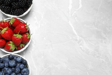 Different ripe berries on light marble table, flat lay. Space for text