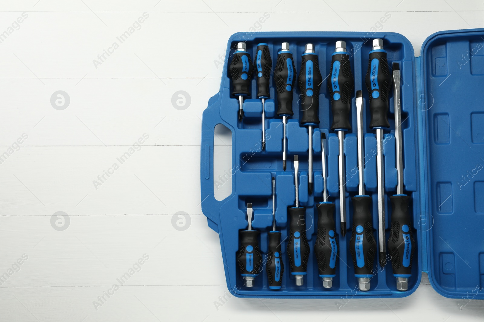 Photo of Set of screwdrivers in open toolbox on white wooden table, top view. Space for text