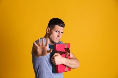 Photo of Greedy man hiding gift box on yellow background