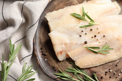 Photo of Raw cod fish, rosemary and spices on table, top view
