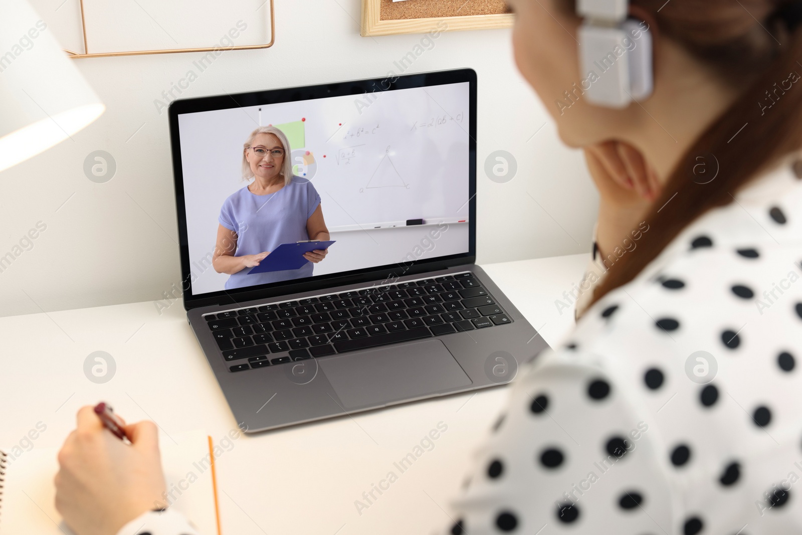 Image of E-learning. Young woman having online lesson with teacher via laptop at home