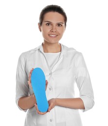 Photo of Beautiful female orthopedist showing insole on white background