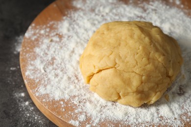Photo of Making shortcrust pastry. Raw dough and flour on grey table, closeup