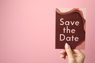 Photo of Woman holding beautiful card with Save the Date phrase on pink background, closeup. Space for text