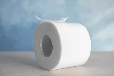 Photo of Toilet paper roll with feather on grey table