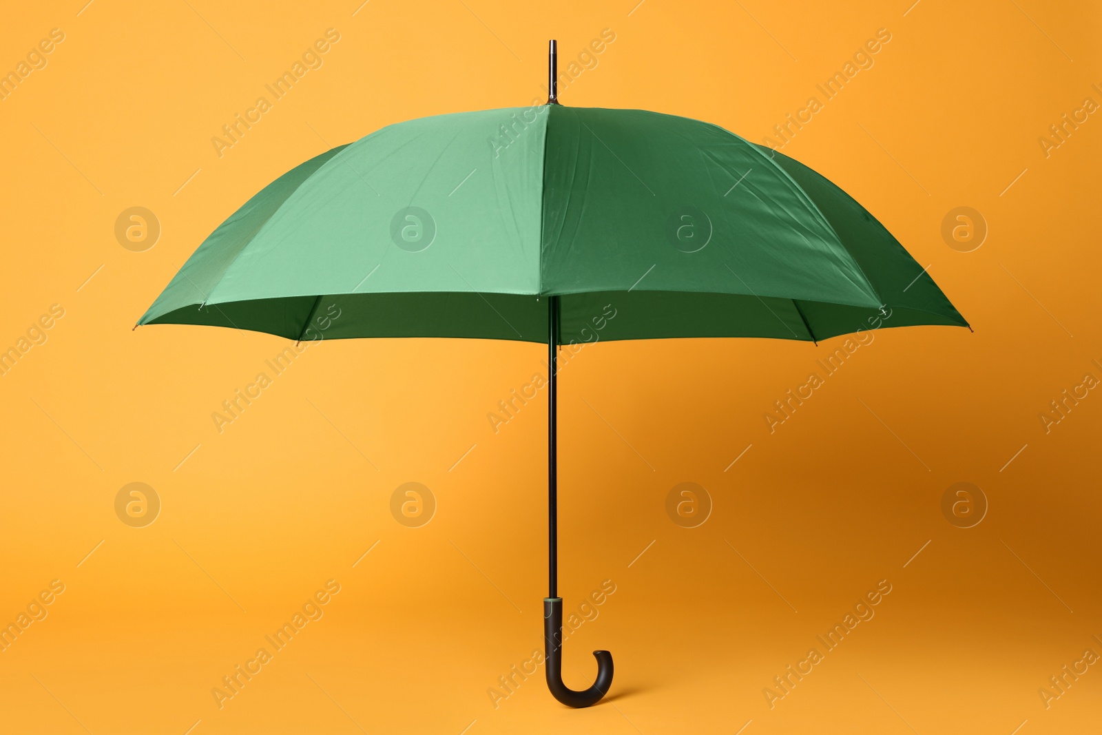 Photo of Stylish open green umbrella on yellow background