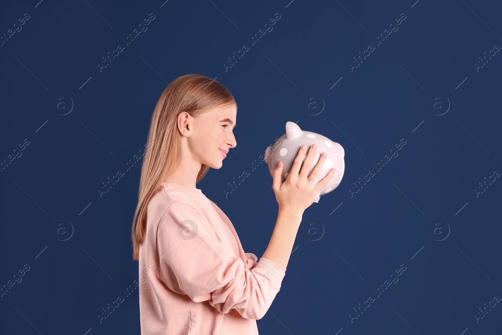 Photo of Teen girl with piggy bank on color background