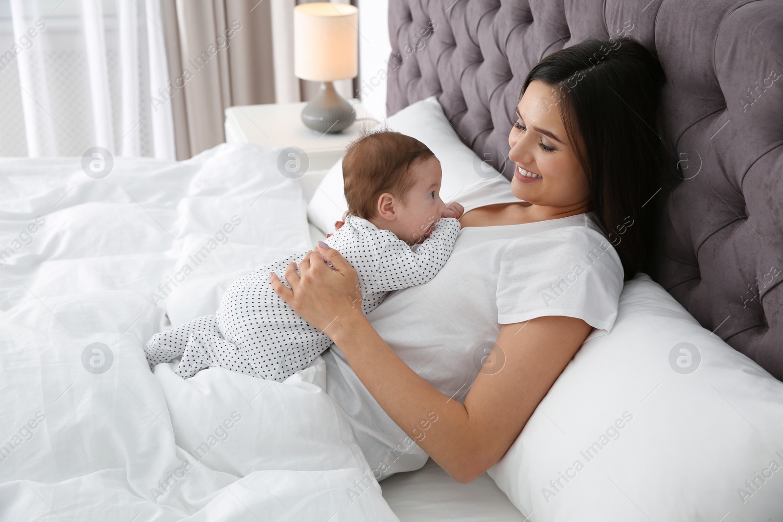 Photo of Happy woman with her cute baby on bed