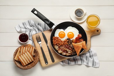 Frying pan with cooked traditional English breakfast on white wooden table, flat lay