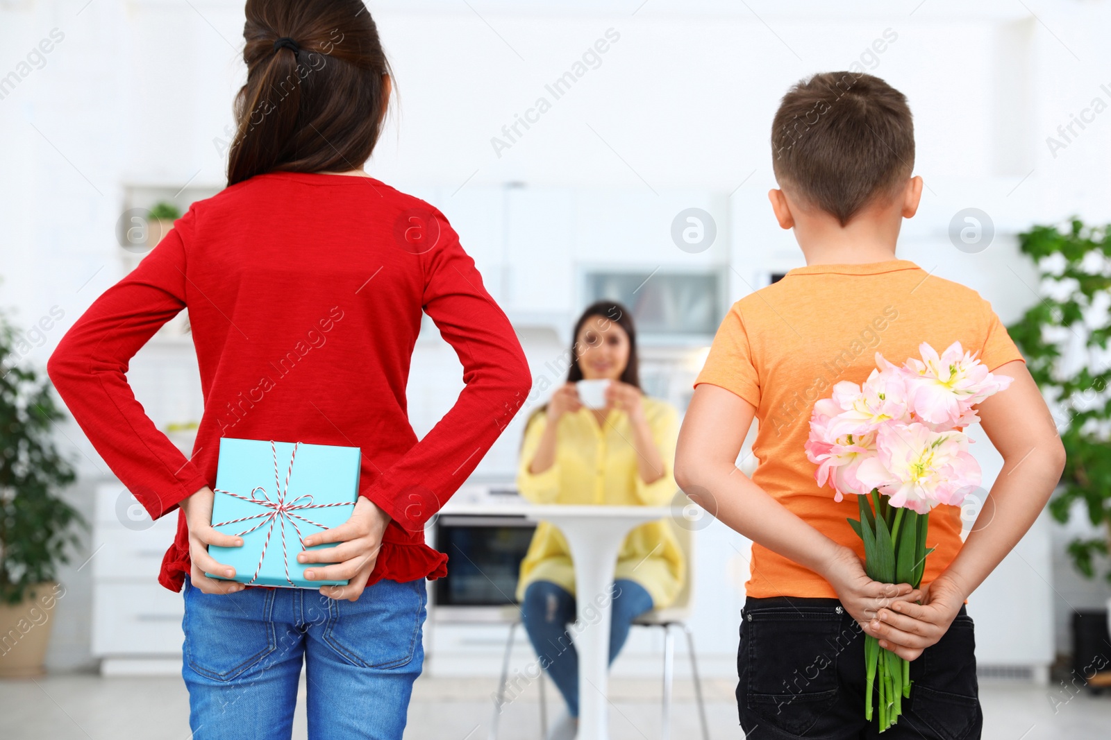 Photo of Son and daughter congratulating mom in kitchen. Happy Mother's Day