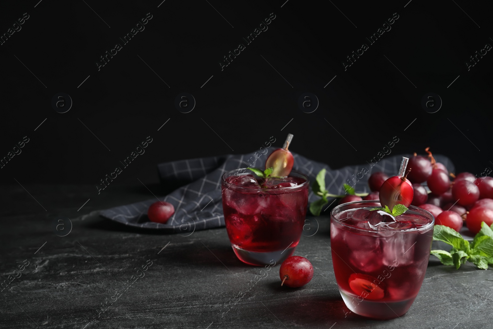 Photo of Delicious grape soda water on black table, space for text. Refreshing drink