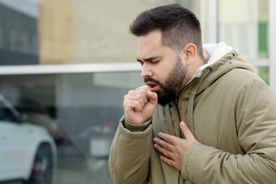 Photo of Sick man coughing outdoors, space for text. Cold symptoms