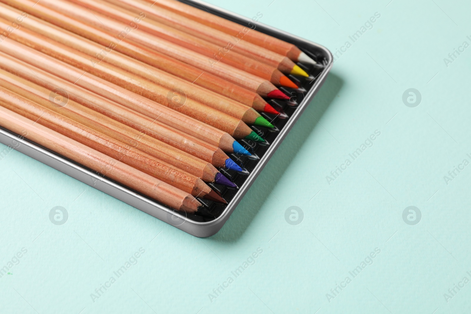 Photo of Box with many colorful pastel pencils on turquoise background, space for text. Drawing supplies