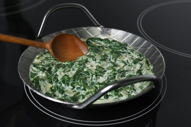 Photo of Woman cooking tasty spinach dip on kitchen stove, closeup view