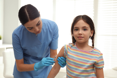 Photo of Doctor vaccinating little child in modern clinic