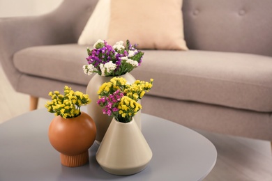 Beautiful flowers in vases as element of interior design on table. Space for text