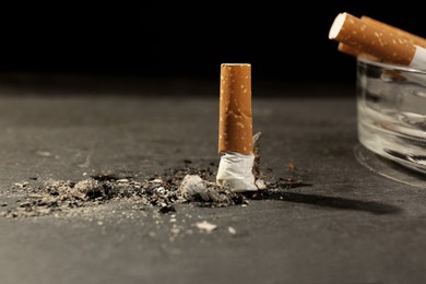 Photo of Ashtray and burnt cigarettes on black table, closeup. No smoking concept