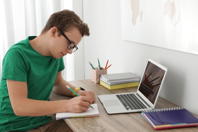 Photo of Teenager boy doing his homework at desk indoors